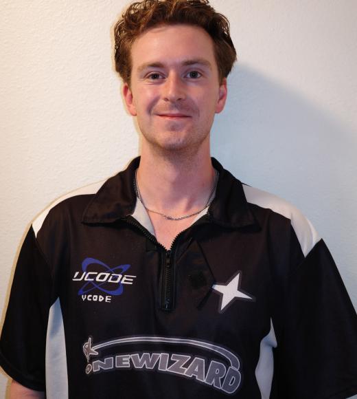Smiling young man with short curly hair wearing black sports jersey against white wall